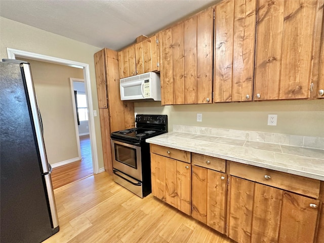 kitchen with appliances with stainless steel finishes and light hardwood / wood-style floors