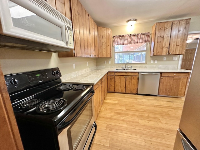 kitchen featuring appliances with stainless steel finishes, sink, and light hardwood / wood-style flooring