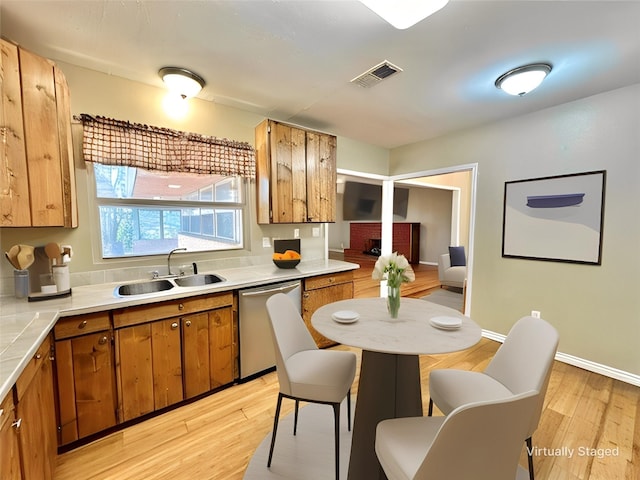 kitchen with dishwasher, sink, and light wood-type flooring