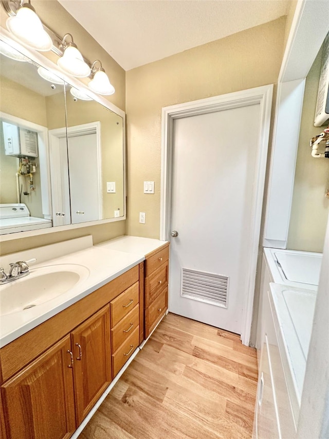 bathroom with washer and dryer, wood-type flooring, and vanity