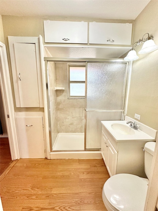 bathroom featuring vanity, hardwood / wood-style floors, an enclosed shower, and toilet