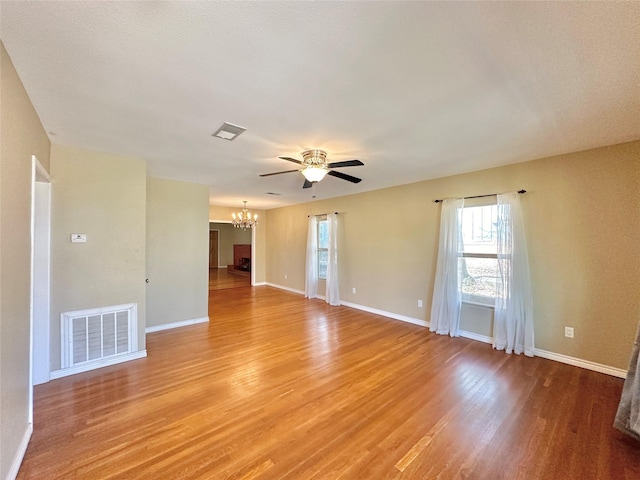 unfurnished room with hardwood / wood-style flooring and ceiling fan with notable chandelier