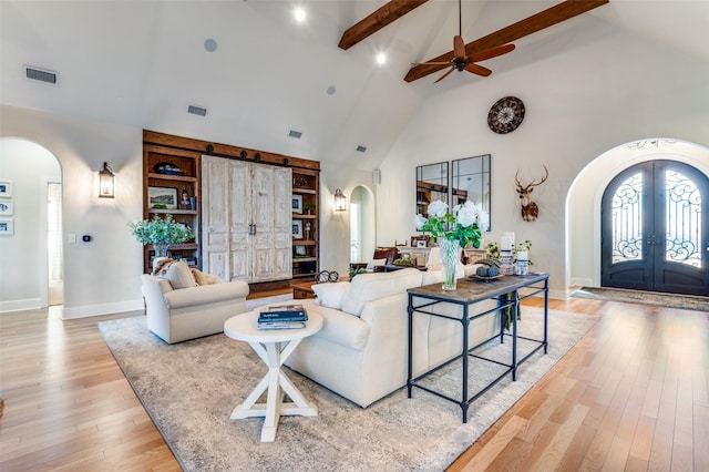 living room with french doors, high vaulted ceiling, light wood-type flooring, beamed ceiling, and ceiling fan