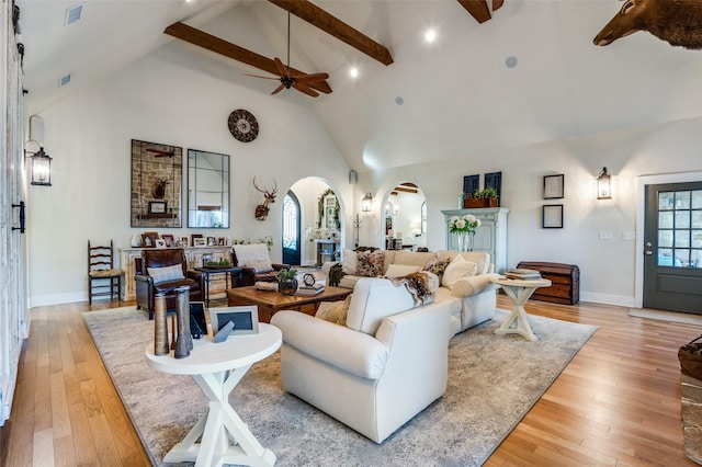 living room with light hardwood / wood-style flooring, high vaulted ceiling, beamed ceiling, and ceiling fan