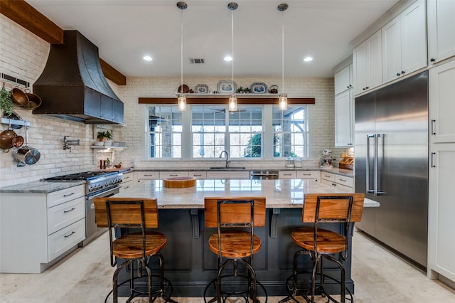 kitchen with premium range hood, a center island, high quality appliances, light stone counters, and decorative light fixtures