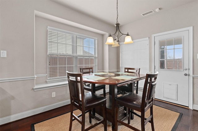 dining room with an inviting chandelier, dark wood-type flooring, baseboards, and visible vents