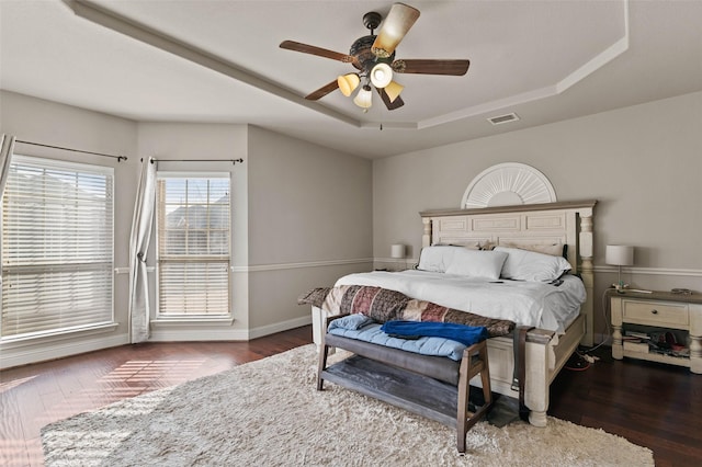 bedroom featuring a tray ceiling, dark wood-type flooring, and ceiling fan