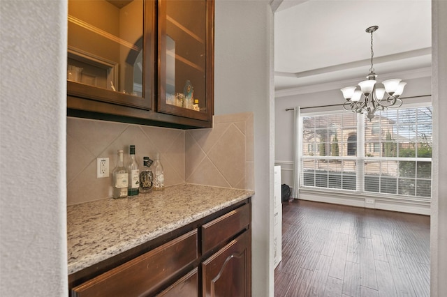 bar featuring tasteful backsplash, dark wood-type flooring, a healthy amount of sunlight, and a chandelier