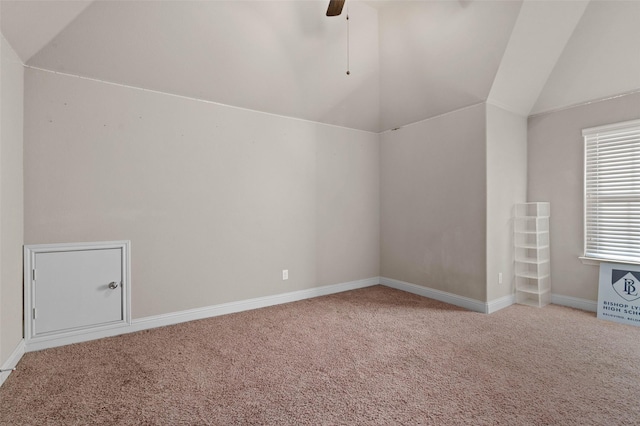 interior space with carpet flooring, a ceiling fan, baseboards, and vaulted ceiling
