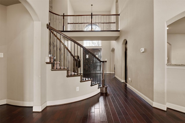 stairs featuring wood-type flooring and a high ceiling