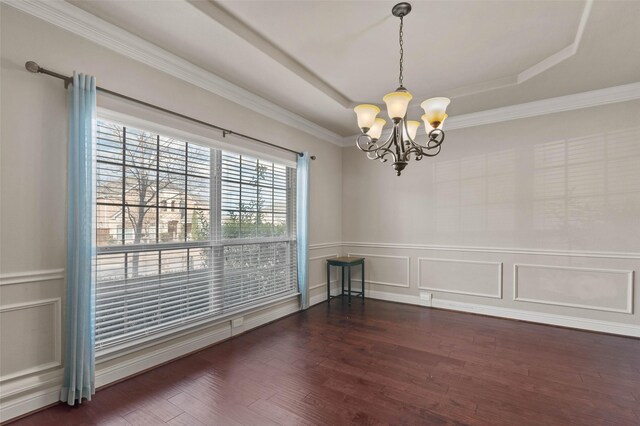 spare room featuring a decorative wall, a chandelier, a raised ceiling, dark wood-type flooring, and wainscoting