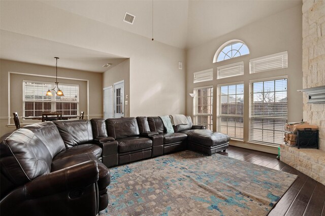 living room featuring ceiling fan, a stone fireplace, dark wood-type flooring, and high vaulted ceiling