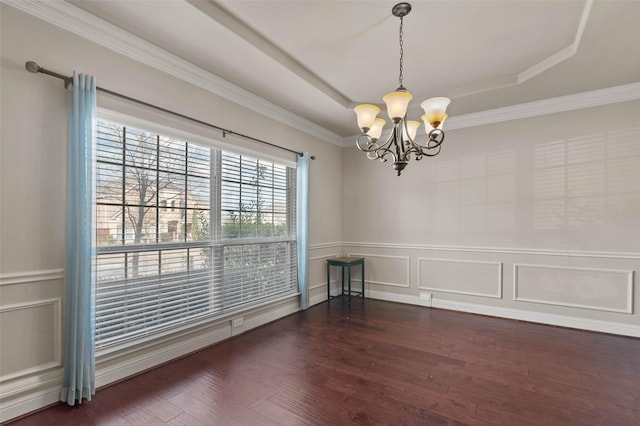 empty room featuring dark hardwood / wood-style flooring, a notable chandelier, a tray ceiling, and crown molding