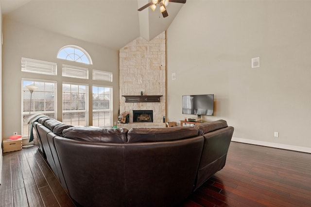living room featuring a fireplace, dark wood-style floors, high vaulted ceiling, and a ceiling fan