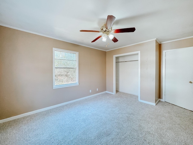 unfurnished bedroom with crown molding, carpet floors, a ceiling fan, baseboards, and a closet