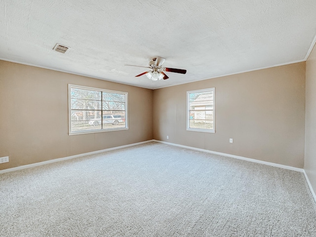 carpeted spare room with a ceiling fan, a textured ceiling, visible vents, baseboards, and ornamental molding