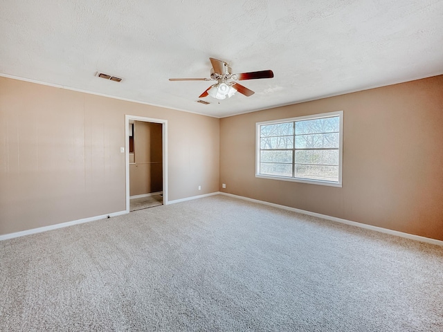 carpeted empty room with baseboards, a ceiling fan, a textured ceiling, and visible vents