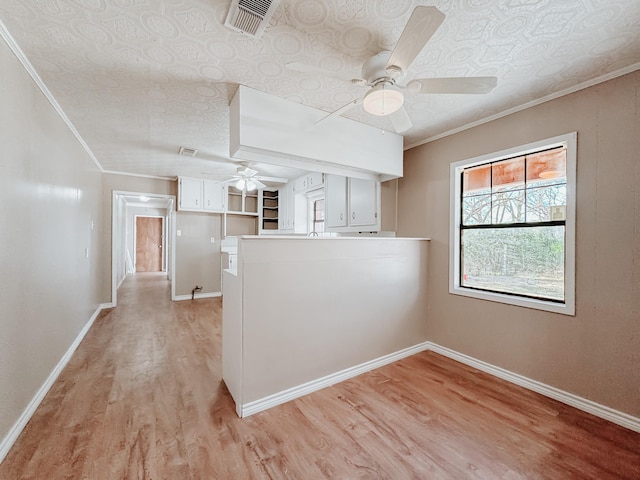 kitchen with ornamental molding, a peninsula, baseboards, ceiling fan, and light wood-style flooring