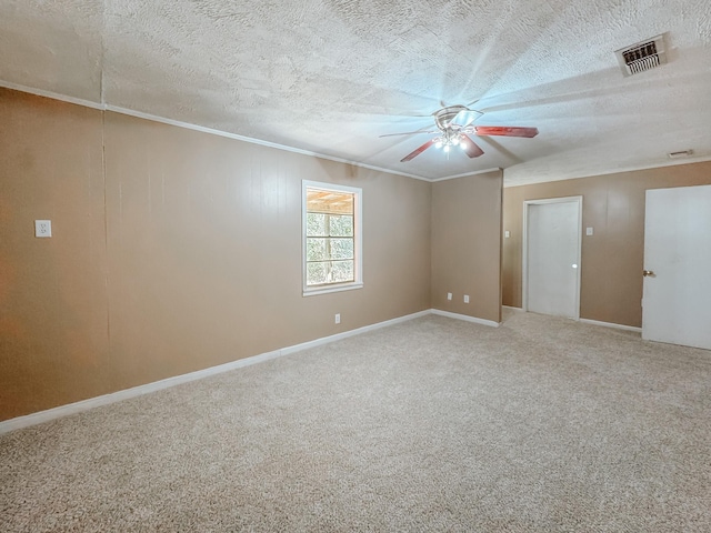 carpeted empty room featuring visible vents, a textured ceiling, ceiling fan, and ornamental molding