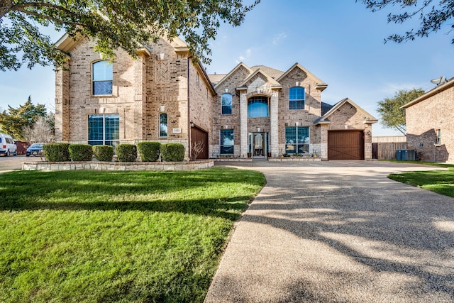 french provincial home featuring driveway, central air condition unit, a front yard, and brick siding