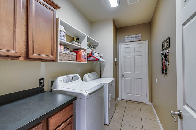 washroom featuring light tile patterned floors, separate washer and dryer, visible vents, baseboards, and cabinet space