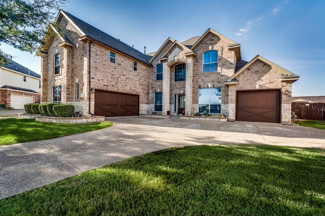 view of front of house with brick siding, a garage, stone siding, driveway, and a front lawn