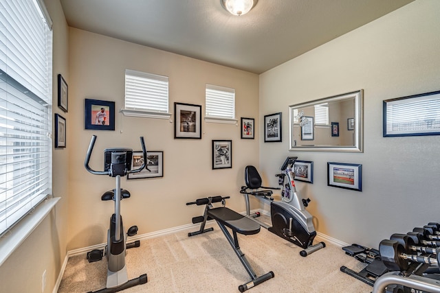 workout area with baseboards and light colored carpet