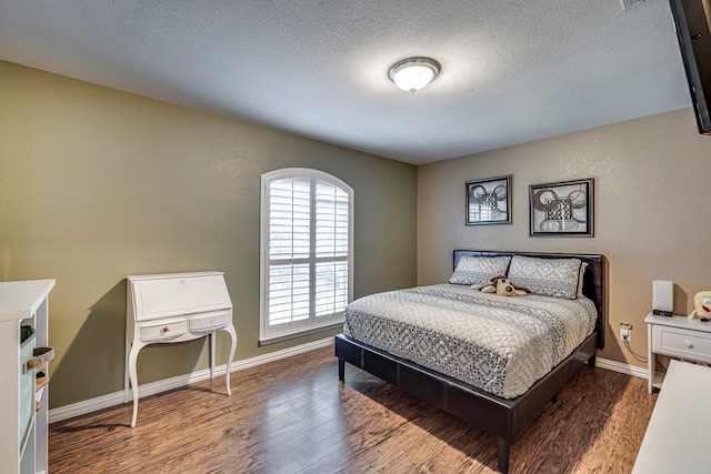 bedroom featuring a textured ceiling, dark wood-type flooring, and baseboards