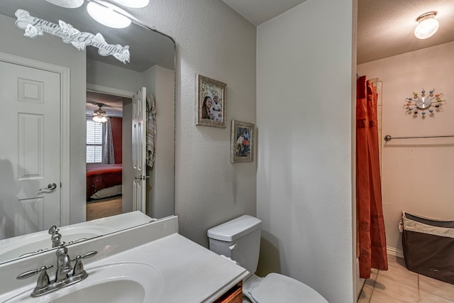 ensuite bathroom with ensuite bathroom, a textured wall, toilet, vanity, and tile patterned floors