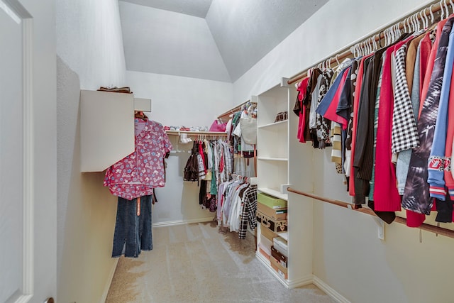 walk in closet with vaulted ceiling and light carpet