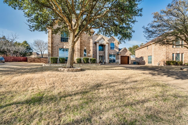 view of front of home featuring brick siding, fence, and a front lawn