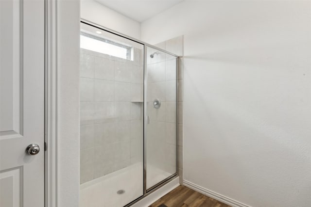 bathroom with wood-type flooring and a shower with shower door