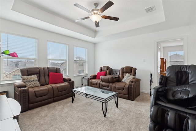 carpeted living room featuring ceiling fan and a tray ceiling