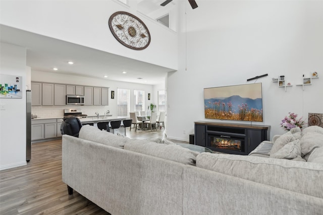 living room with sink, hardwood / wood-style flooring, ceiling fan, and a high ceiling