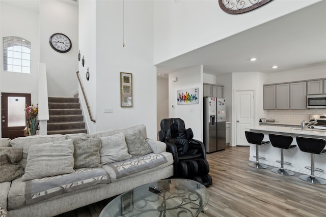 living room featuring a towering ceiling and light wood-type flooring