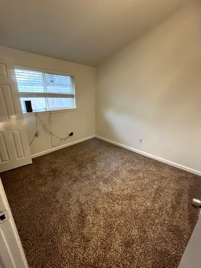 spare room featuring dark carpet