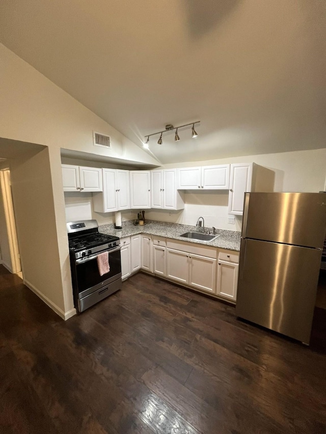 kitchen with lofted ceiling, sink, white cabinets, stainless steel appliances, and dark wood-type flooring