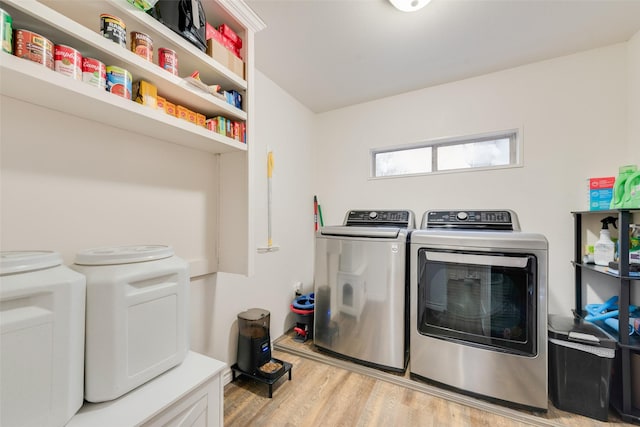 clothes washing area with washer and clothes dryer and light wood-type flooring