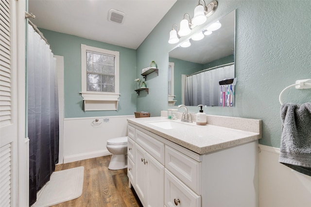 bathroom featuring vanity, hardwood / wood-style floors, a notable chandelier, and toilet