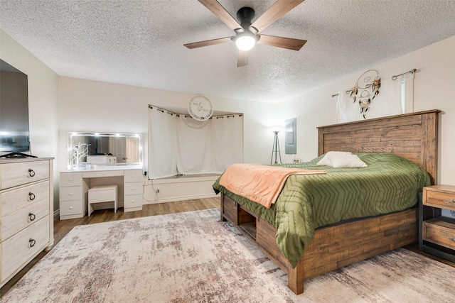 bedroom featuring ceiling fan, light hardwood / wood-style floors, and a textured ceiling