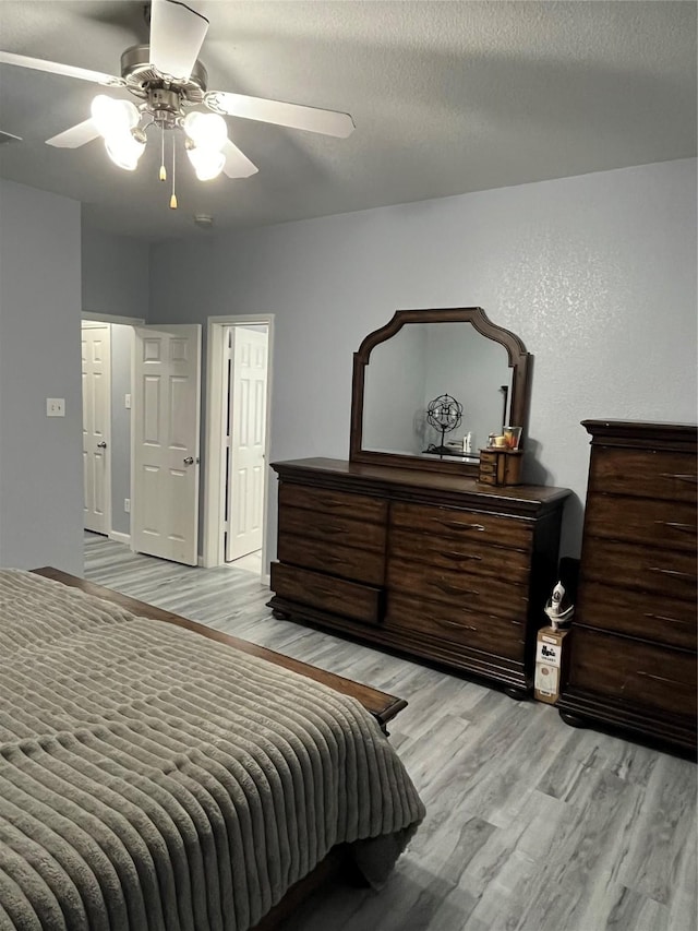 bedroom with ceiling fan, light hardwood / wood-style floors, and a textured ceiling