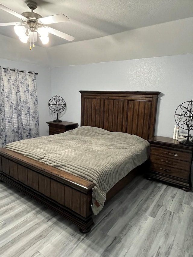 bedroom with ceiling fan, a textured ceiling, and light hardwood / wood-style floors