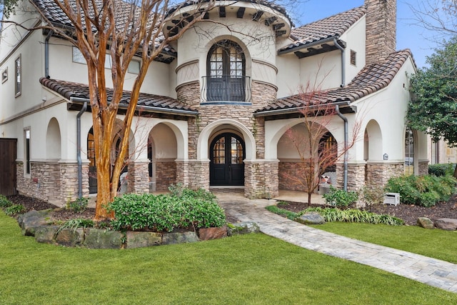 mediterranean / spanish-style home with french doors, a tile roof, a chimney, stucco siding, and a front yard