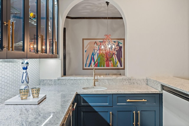 kitchen featuring arched walkways, tasteful backsplash, glass insert cabinets, a sink, and light stone countertops