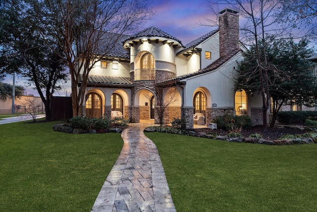 mediterranean / spanish-style home featuring a yard and a balcony