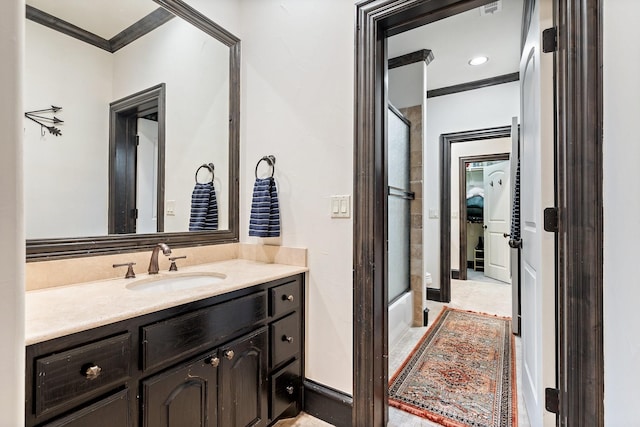 bathroom featuring enclosed tub / shower combo, crown molding, and vanity