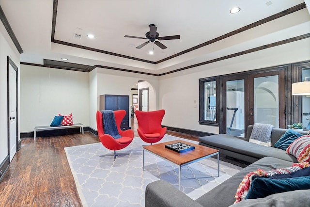 living room featuring dark hardwood / wood-style flooring, ceiling fan, a raised ceiling, crown molding, and french doors