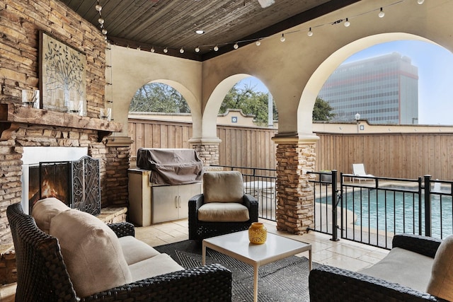 view of patio / terrace with area for grilling, a fenced in pool, grilling area, and an outdoor stone fireplace