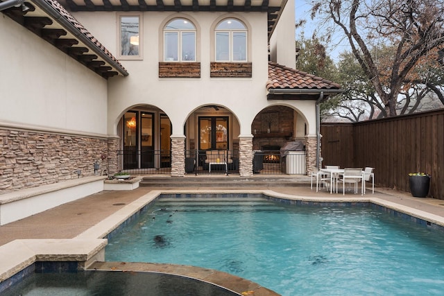 view of swimming pool with french doors, a pool with connected hot tub, outdoor dining space, a patio area, and fence