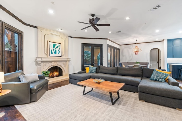 living room featuring crown molding, ceiling fan, a fireplace, and light hardwood / wood-style floors